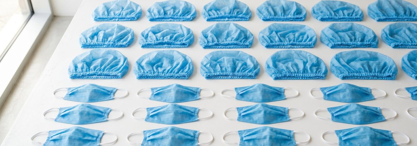 Disposable blue bouffant caps and beard covers neatly arranged on a bright surface