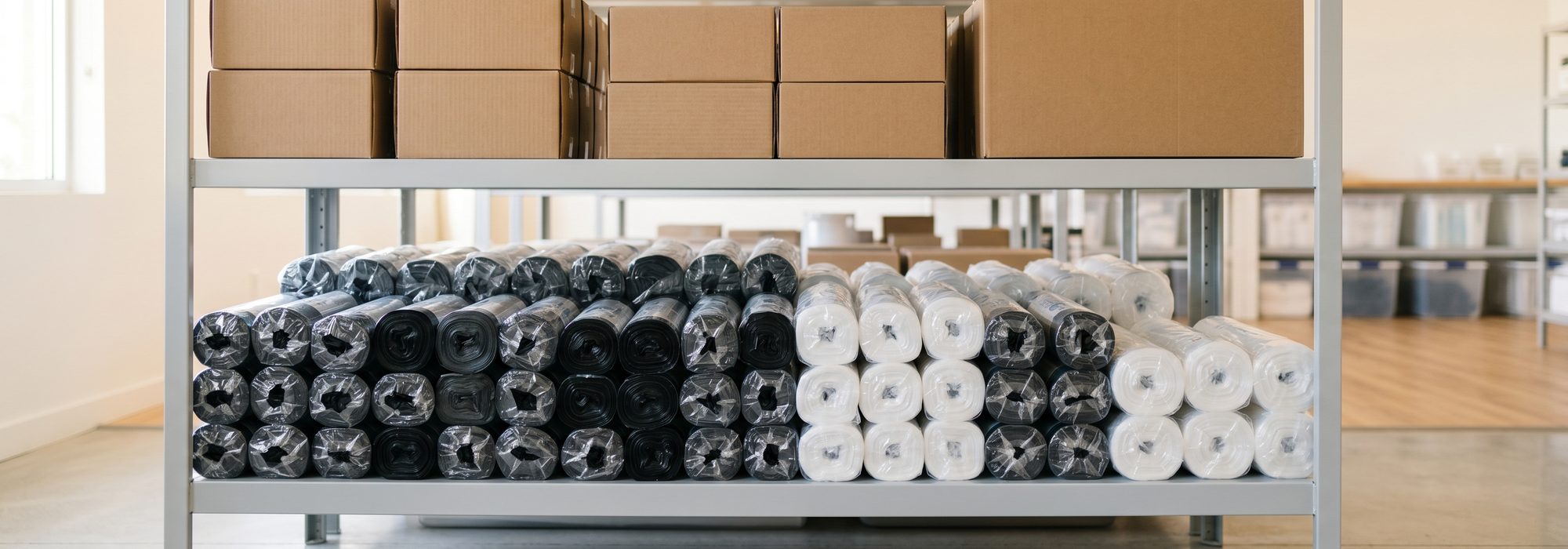 Plain boxes and rolls of black and clear trash can liners on bright shelving