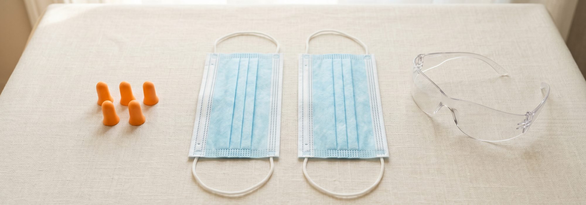 Disposable face masks, foam earplugs and clear safety glasses flat-lay
